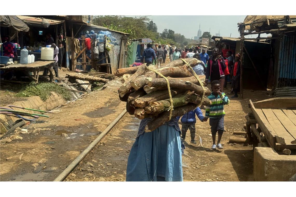 Eine Frau trägt ein Bündel Brennholz entlang der Bahnstrecke, die durch Nairobis größten Slum Kibera führt. (Archivbild)