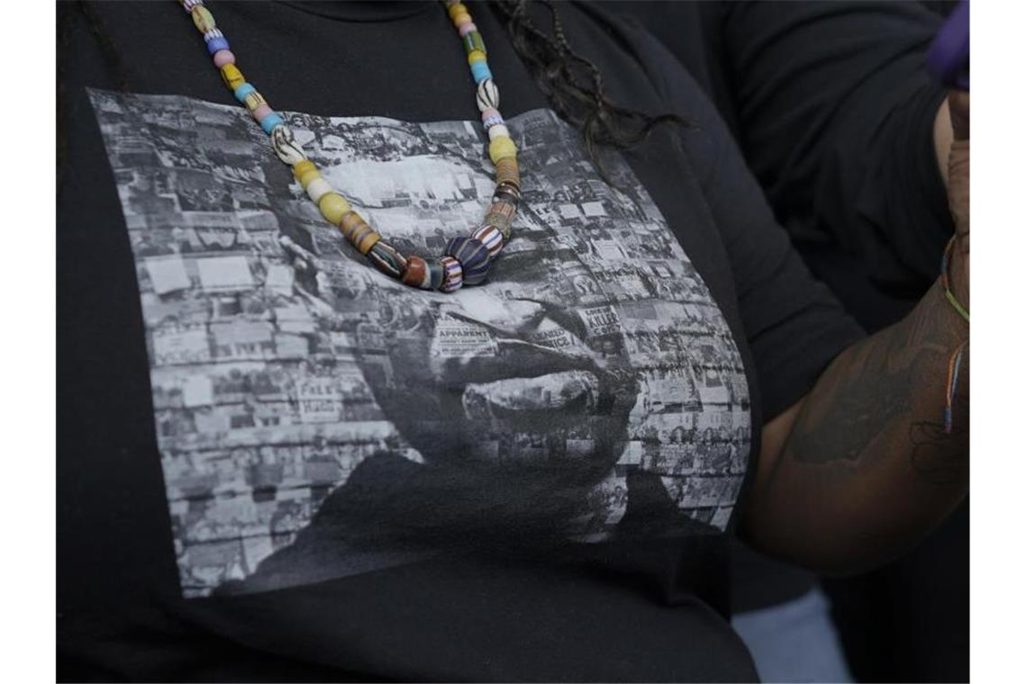 Eine Frau trägt ein T-Shirt mit einem Bild von George Floyd, während sie und andere Unterstützer die Anhörung zur Verurteilung des Ex-Polizisten Derek Chauvin verfolgen. Foto: Julio Cortez/AP/dpa