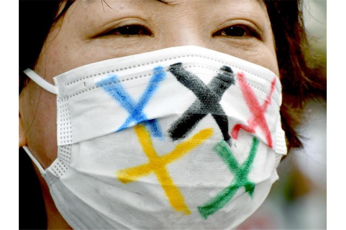 Eine Frau trägt einen Mund-Nasen-Schutz mit den Farben der fünf olympischen Ringe während der Ankunft der olympischen Fackel in Tokio. Foto: Ramiro Agustin Vargas Tabares/ZUMA Press Wire/dpa