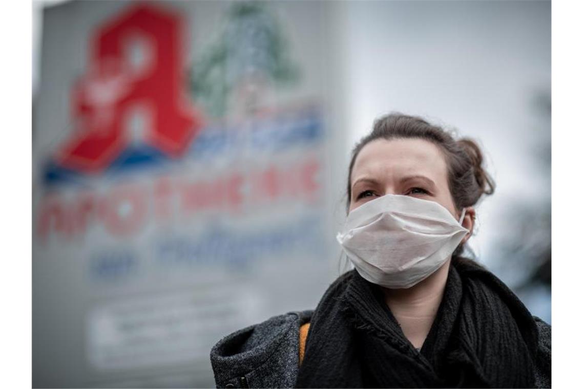 Eine Frau trägt vor einer Apotheke eine Mund- und Nasenmaske. Foto: Fabian Strauch/dpa/Archivbild