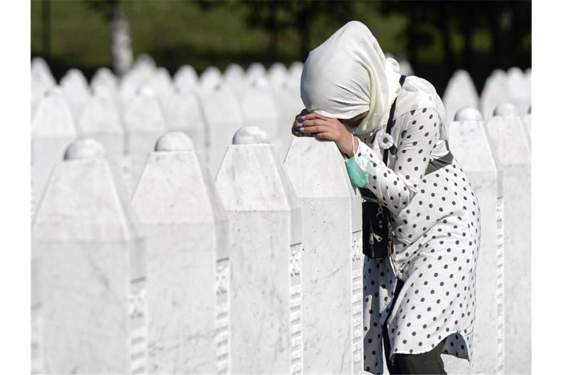 Eine Frau trauert auf dem Friedhof der Gedenkstätte Potocari in der Nähe von Srebrenica an einem Grab. Foto: Kemal Softic/AP/dpa