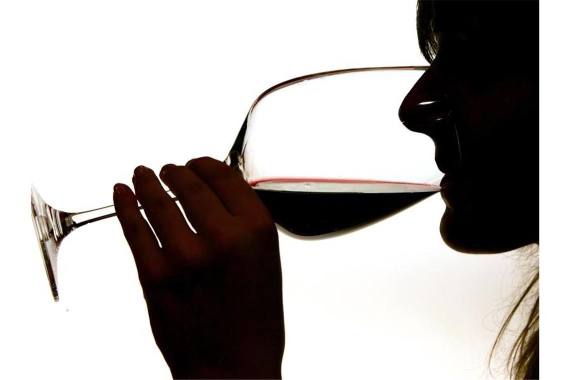 Eine Frau trinkt aus einem Rotweinglas. Foto: Gero Breloer/Archivbild