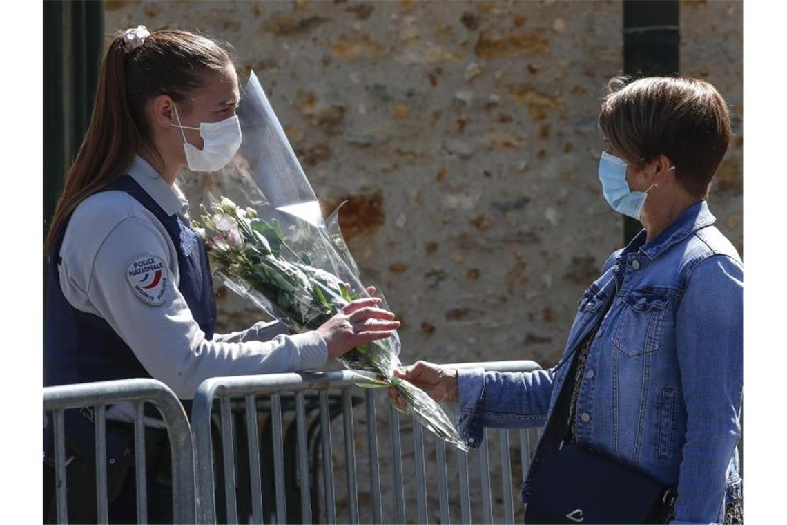 Eine Frau überreicht einer Polizeibeamtin Blumen. Foto: Michel Euler/AP/dpa