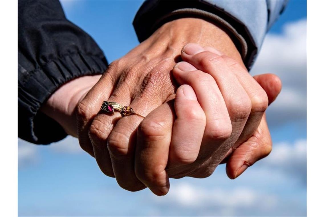 Eine Frau und ein Mann halten sich bei einem Spaziergang an den Händen. Foto: Axel Heimken/dpa/Symbolbild