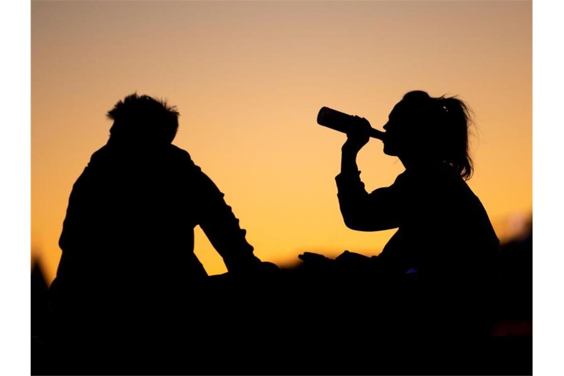 Eine Frau und ein Mann sitzen in der Abenddämmerung. Foto: Marius Becker/dpa/Archivbild