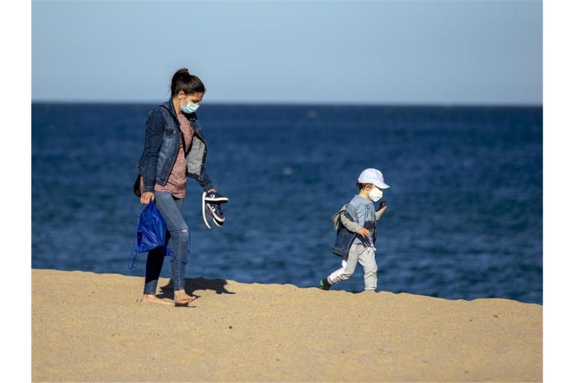 Trotz erster Lockerungen: Urlaubspläne noch auf Sand gebaut Eine Frau und ihr Sohn an einem Strand in der Nähe von Barcelona in Spanien. Foto: Emilio Morenatti/AP/dpa