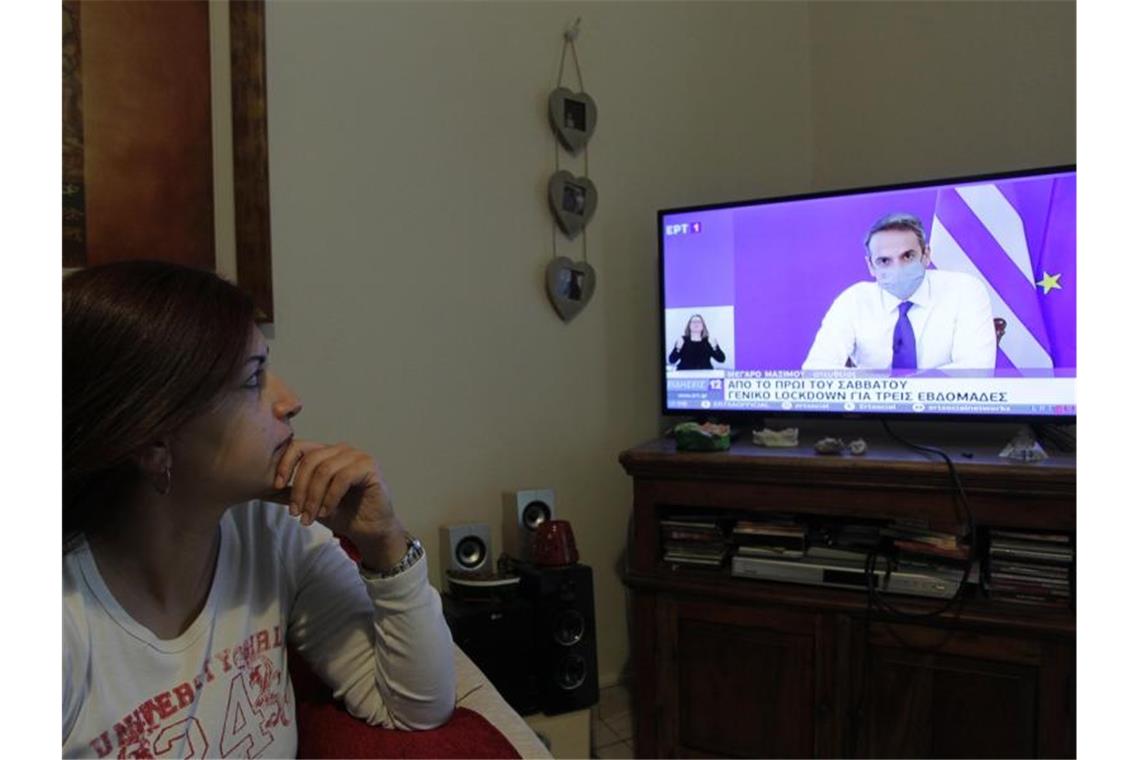 Eine Frau verfolgt die TV-Ansprache von Griechenlands Premierminister Mitsotakis. Foto: Aristidis Vafeiadakis/ZUMA Wire/dpa
