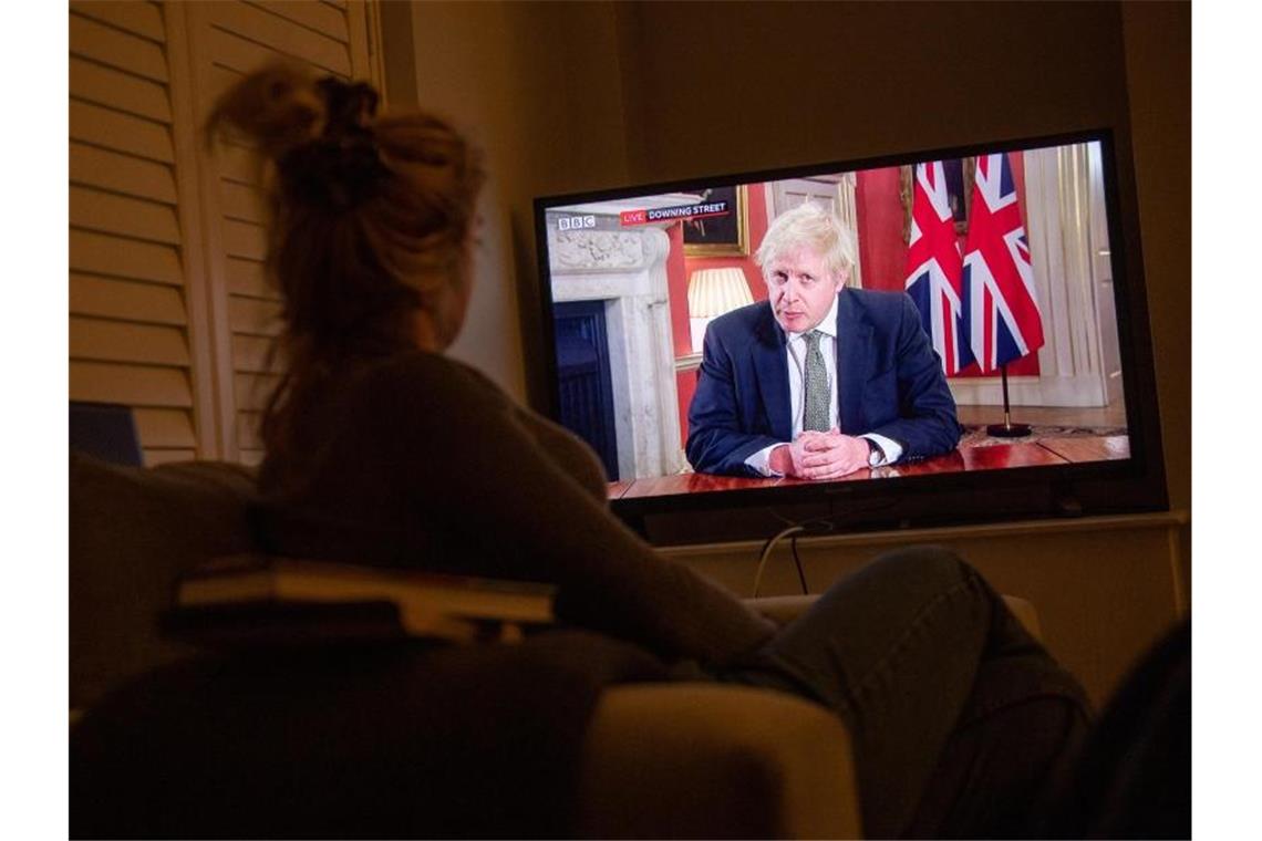 Eine Frau verfolgt im Fernsehen die Ansprache von Premierminister Boris Johnson an die Nation. Foto: Jacob King/PA Wire/dpa