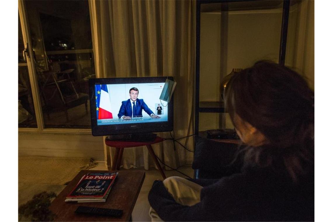 Eine Frau verfolgt in Paris die TV-Ansprache von Staatspräsident Emmanuel Macron. Foto: Sadak Souici/Le Pictorium Agency via ZUMA/dpa