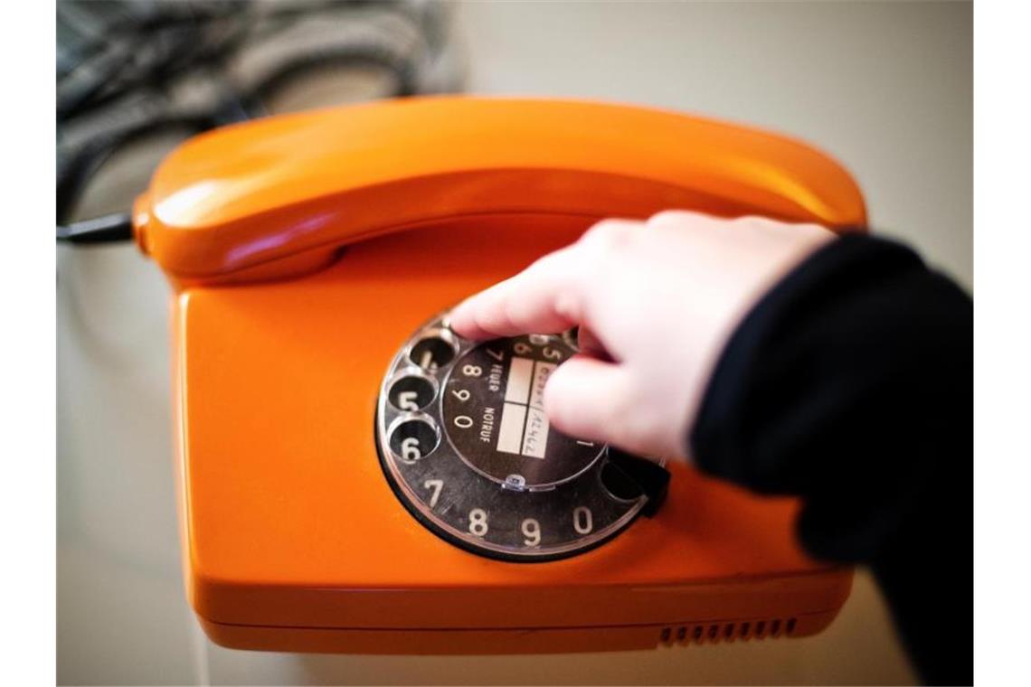 Eine Frau wählt mit einem alten Telefon mit Wählscheibe eine Telefonnummer. Foto: Jan-Philipp Strobel/dpa/Symbolbild