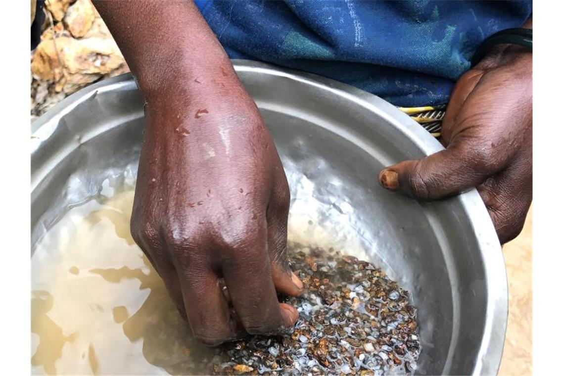 Eine Frau wäscht in der Mine Zola Zola bei Nzibira in der ostkongolesischen Provinz Süd-Kivu auf der Suche nach wertvollen Mineralien Gestein aus. Über weltweite Lieferketten gelangen sie in Handys und Autos. Foto: Jürgen Bätz/dpa