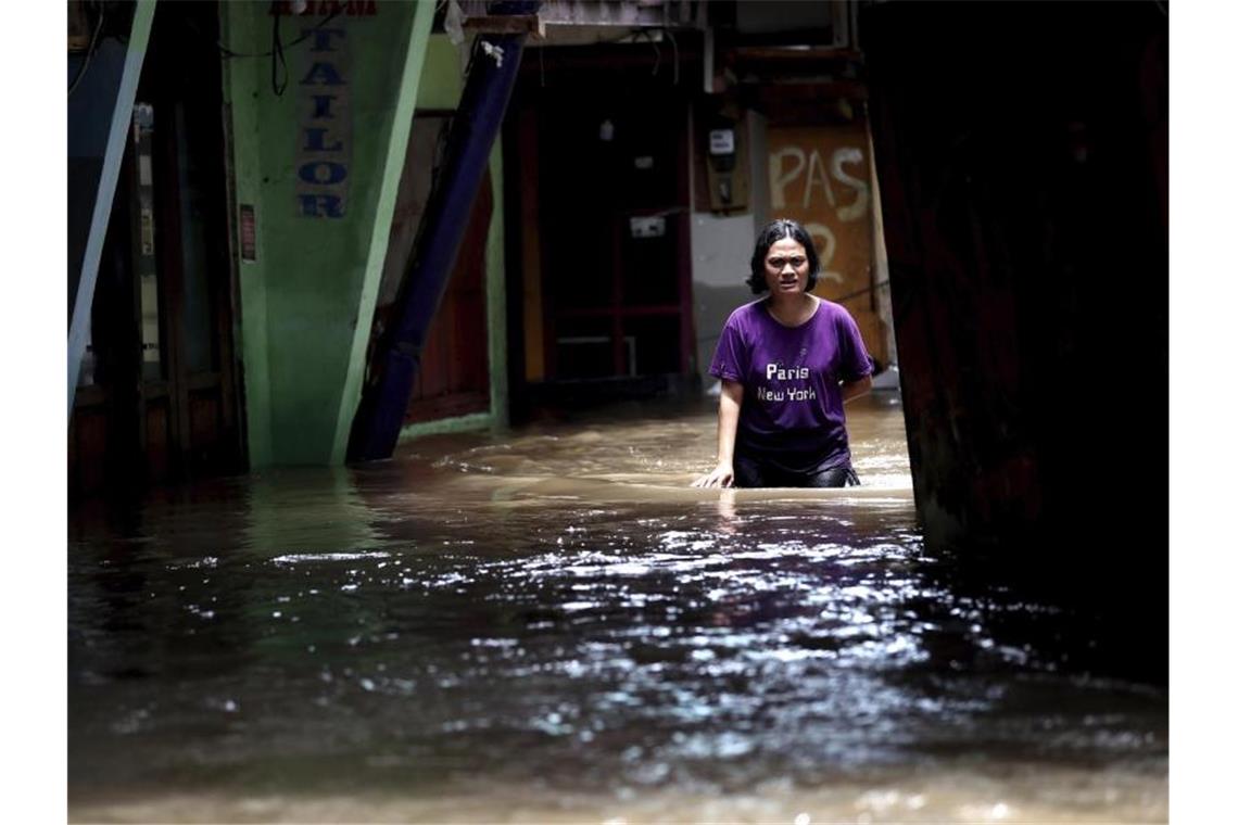 Eine Frau watet durch das Hochwasser einer überschwemmten Straße in Jakarta. Foto: Tatan Syuflana/AP/dpa