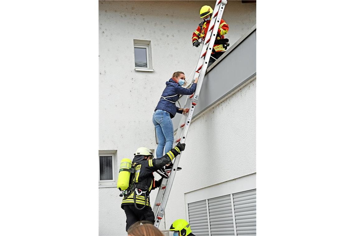 Eine Frau wird, gesichert mit einem Seil, vom Dach eines Gebäudes geholt.