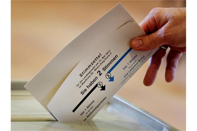 Eine Frau wirft in einem Wahllokal ihren Stimmzettel in die Wahlurne. Foto: Oliver Berg/dpa/Symbol