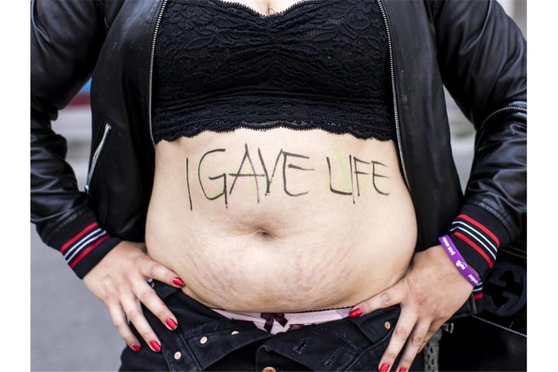 Eine Frau zeigt ihren Bauch mit der Aufschrift „I gave life“ („Ich habe Leben gegeben“). Foto: Alexandra Wey/Keystone