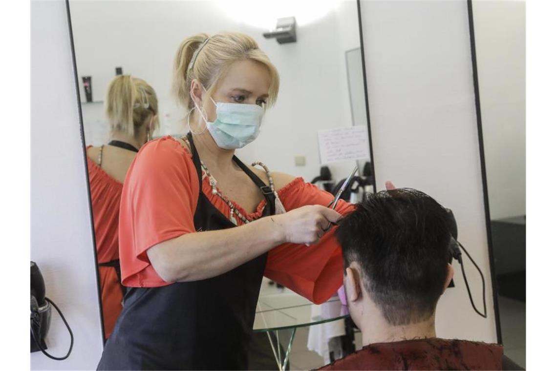Eine Friseurin mit Mundschutz schneidet einem Kunden die Haare. Foto: Thierry Roge/BELGA/dpa