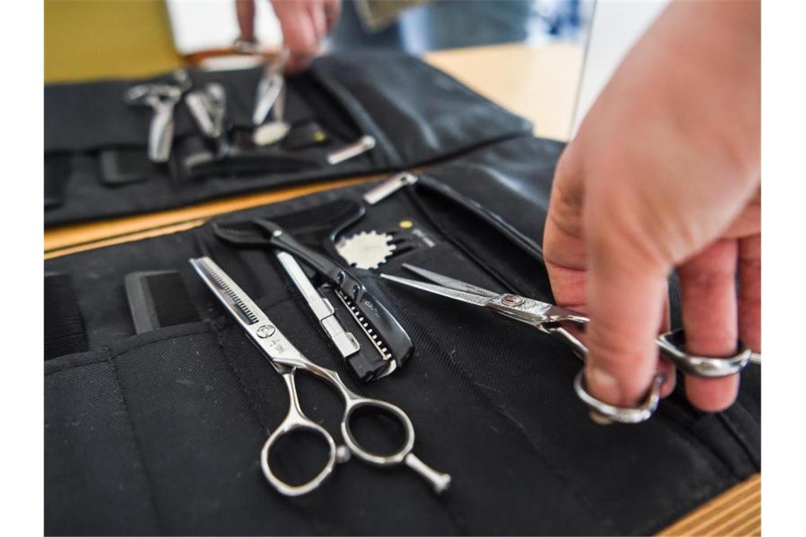 Friseure und Baumärkte wieder offen: Ansturm blieb aus Eine Friseurin nimmt eine Haarschere aus ihrer Tasche. Foto: Kira Hofmann/dpa-Zentralbild/dpa/Symbolbild