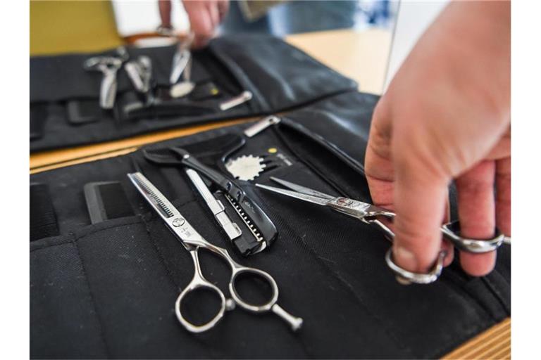 Eine Friseurin nimmt eine Haarschere aus ihrer Tasche. Foto: Kira Hofmann/dpa-Zentralbild/dpa/Symbolbild