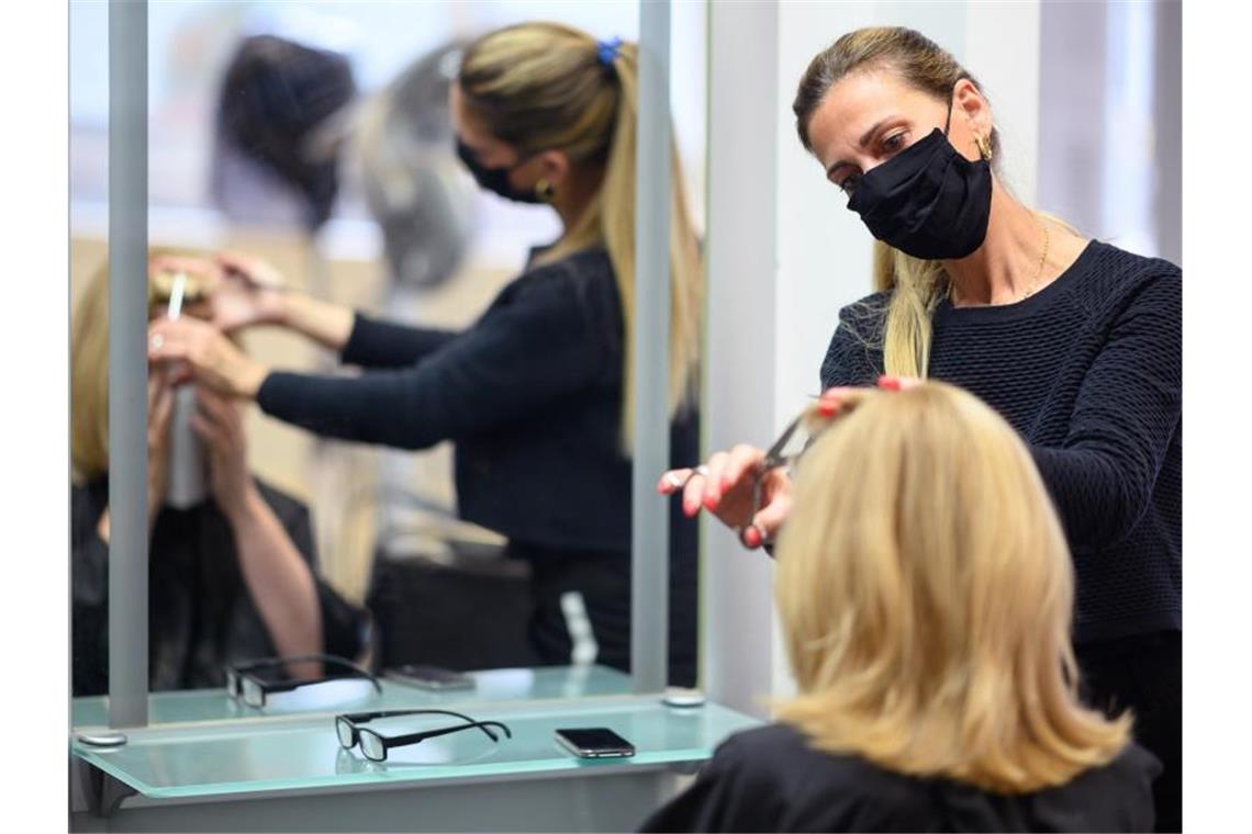 Eine Friseurin schneidet in einem Friseursalon den Pony einer Kundin. Foto: Sebastian Gollnow/dpa/Archivbild