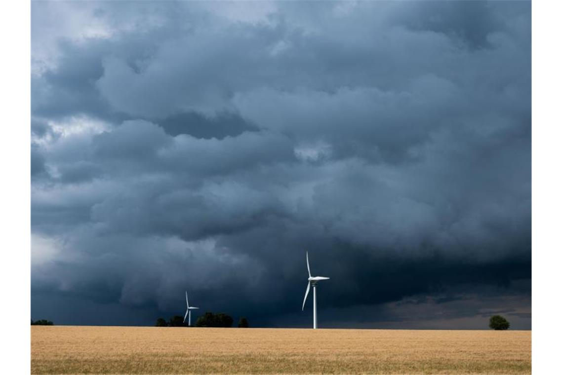 Eine Gewitterzelle mit dunklen Wolken zieht über Windräder in der Region Hannover hinweg. Foto: Julian Stratenschulte/dpa