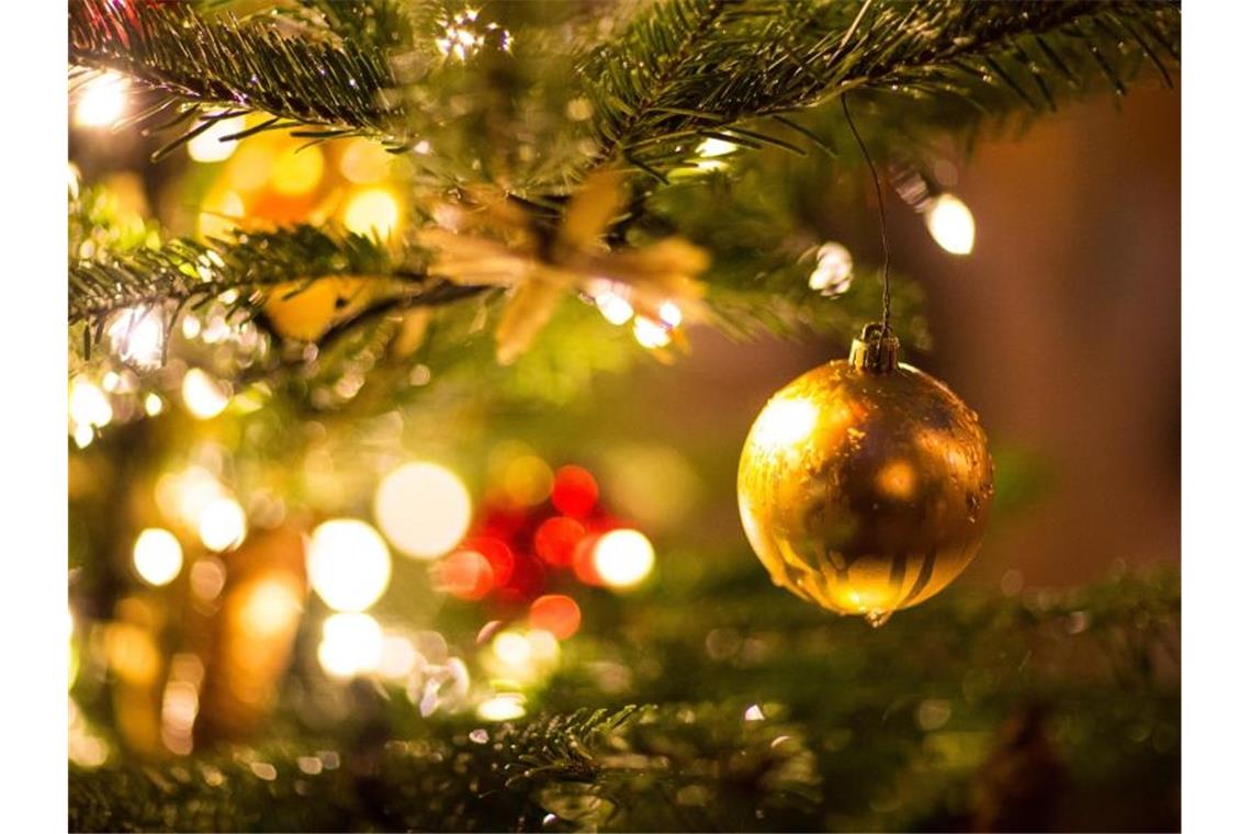Eine goldene Kugel hängt an einem Weihnachtsbaum. Foto: Friso Gentsch/dpa/Archivbild