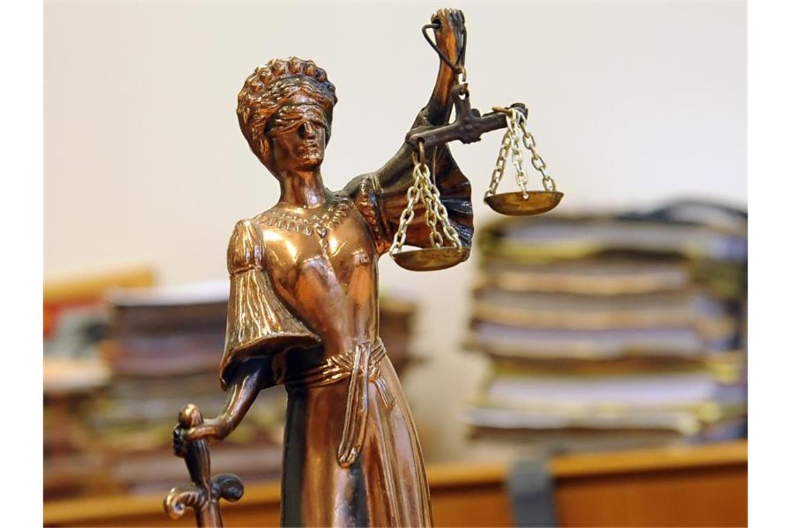 Eine goldfarbene Justitia-Figur steht vor Aktenbergen, die sich auf einem Tisch stapeln. Foto: Britta Pedersen/dpa-Zentralbild/dpa/Symbolbild