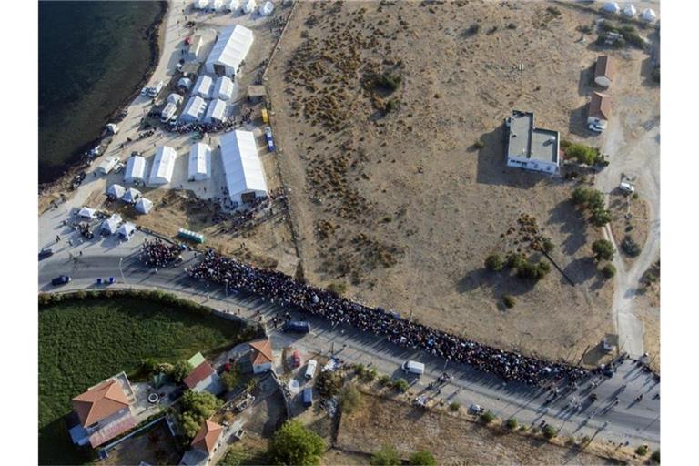 Eine größere Gruppe von Migranten wartet darauf, in das neue provisorische Flüchtlingslager gelassen zu werden. Foto: Petros Giannakouris/AP/dpa