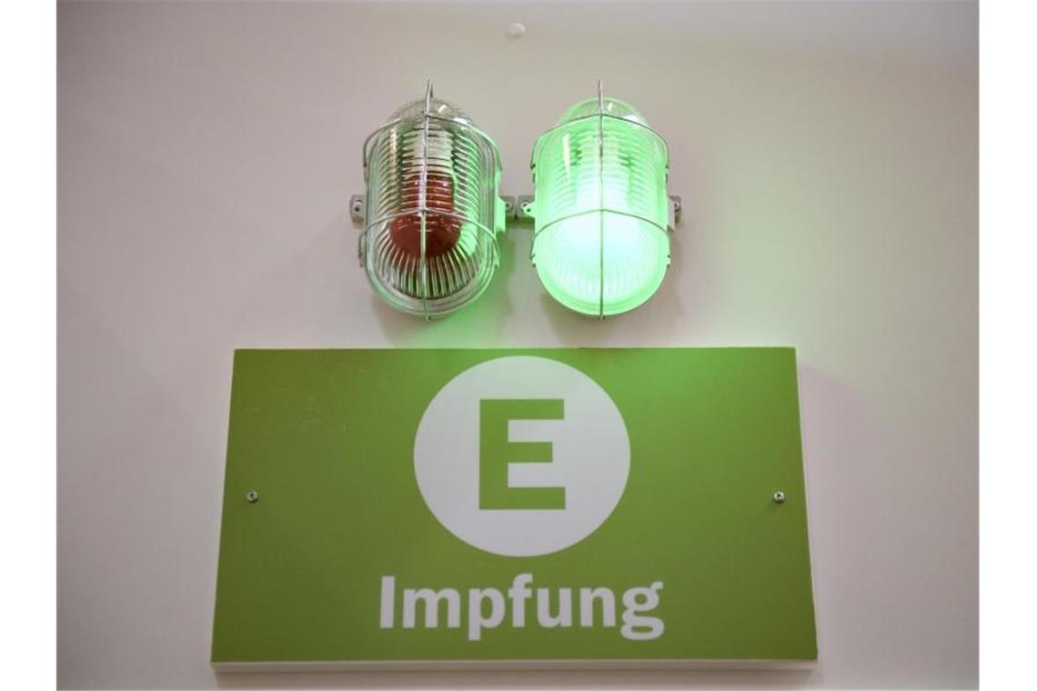 Eine grüne Lampe leuchtet am Eingang eines Impfzentrums. Experten gehen davon aus, dass eine Herdenimmunität gegen das Coronavirus ohne die Impfung von Kindern und Jugendlichen nicht erreichbar ist. Foto: Christopher Neundorf/dpa