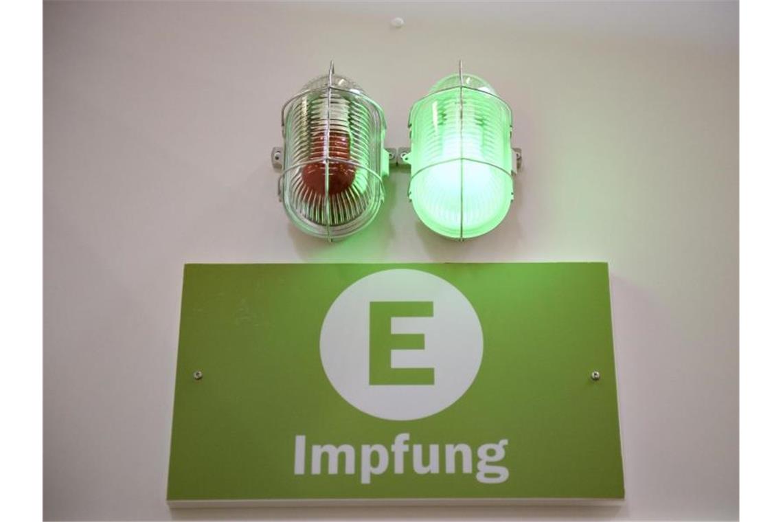 Eine grüne Lampe leuchtet am Eingang eines Corona-Impfzentrums. Foto: Christopher Neundorf/dpa/Symbolbild