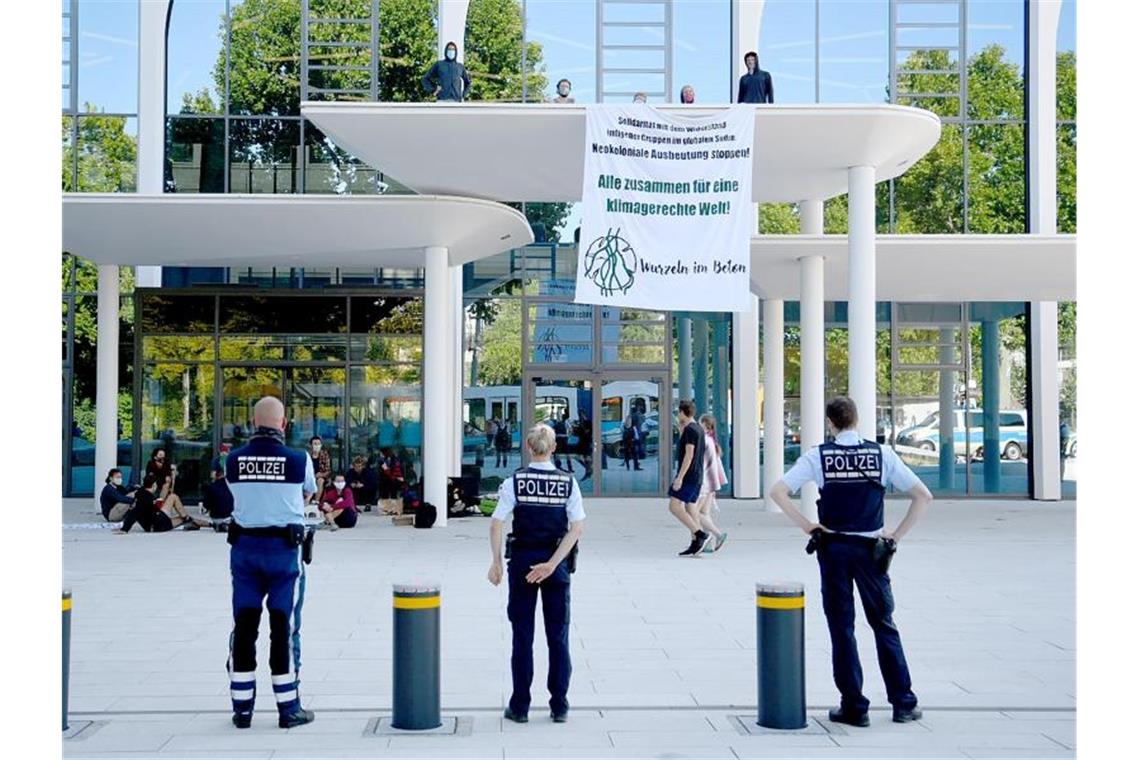 Eine Gruppe von Klimaaktivisten protestiert mit einem Transparent vor der Zentrale des Zementherstellers HeidelbergCement. Foto: Rene Priebe/dpa