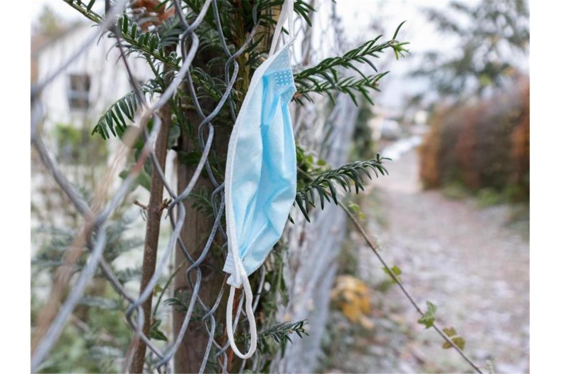 Weggeworfene Masken sind Gefahr für Wildtiere Eine hängen gelassene Maske ist an einem Zaun an einem Gehweg zu sehen. Foto: Bernd Weißbrod/dpa/Archivbild