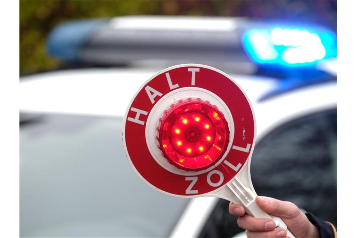 Zoll pfändet Bus: Reisende müssen umsteigen Eine Haltekelle des Zolls wird vor das Blaulicht eines Einsatzfahrzeuges gehalten. Foto: Sebastian Willnow/dpa-Zentralbild/dpa/Symbolbild