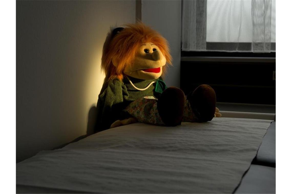 Kinderpornografie-Ermittlungen: Datenträger werden geprüft Eine Handpuppe sitzt auf einer Liege in einem Untersuchungsraum in der Kinderschutzambulanz. Foto: Julian Stratenschulte/dpa/Archivbild