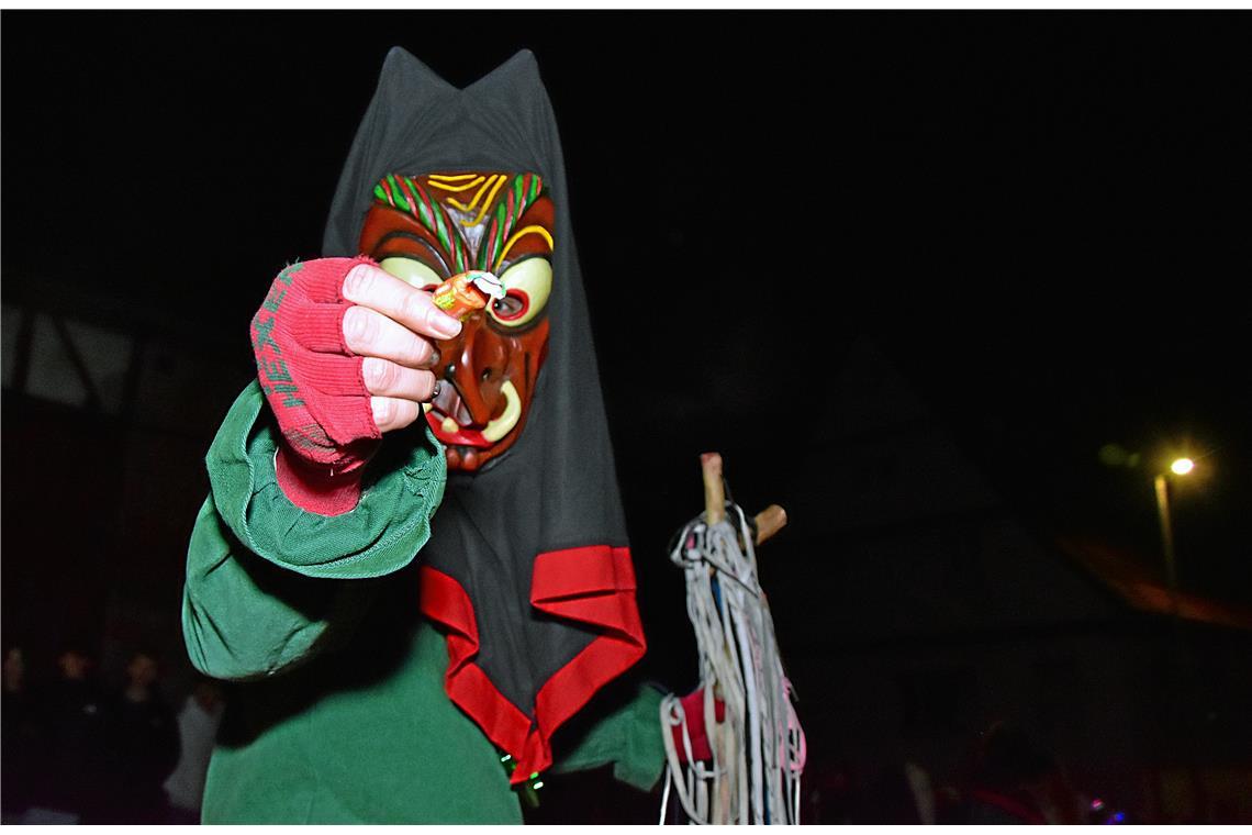 Eine Hexe verteilt Bonbons an die Umzugsgäste. Nachtumzug der Schbiallomba-Schlo...