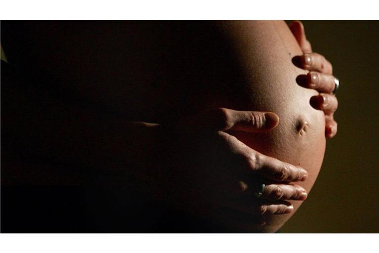 Eine hochschwangere Frau fasst sich mit beiden Händen an ihren Bauch. Auch Nicht-Trinker leiden in vielen Fällen unter den Folgen von Alkoholkonsum: So schädigen trinkende Mütter ihre ungeborenen Kinder.