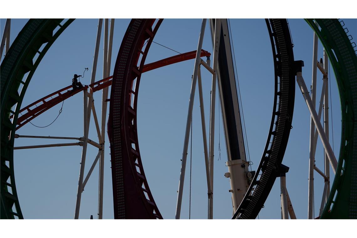Eine Höhenkletterin nimmt in luftiger Höhe während der Aufbauarbeiten des Frühlingsdoms eine Schiene der Achterbahn auf dem Heiligengeistfeld in Hamburg entgegen.