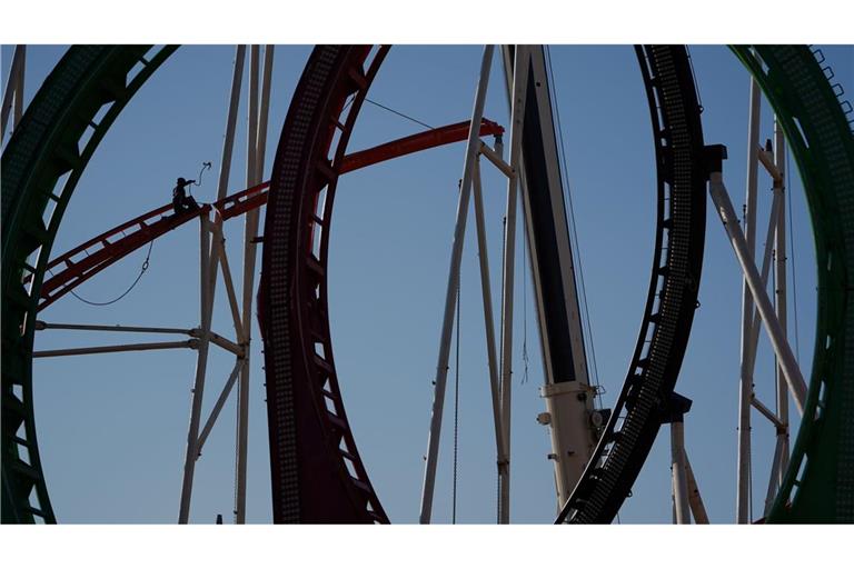 Eine Höhenkletterin nimmt in luftiger Höhe während der Aufbauarbeiten des Frühlingsdoms eine Schiene der Achterbahn auf dem Heiligengeistfeld in Hamburg entgegen.