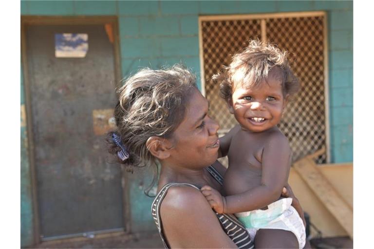 Eine indgene Mutter und ihr Kind in Ramingining im Northern Territory (Archivbild). Seit Jahrzehnten forderten Aborigines-Verbände finanzielle Entschädigungen für die Menschenrechtsverletzungen. Foto: Lucy Hughes Jones/AAP/dpa