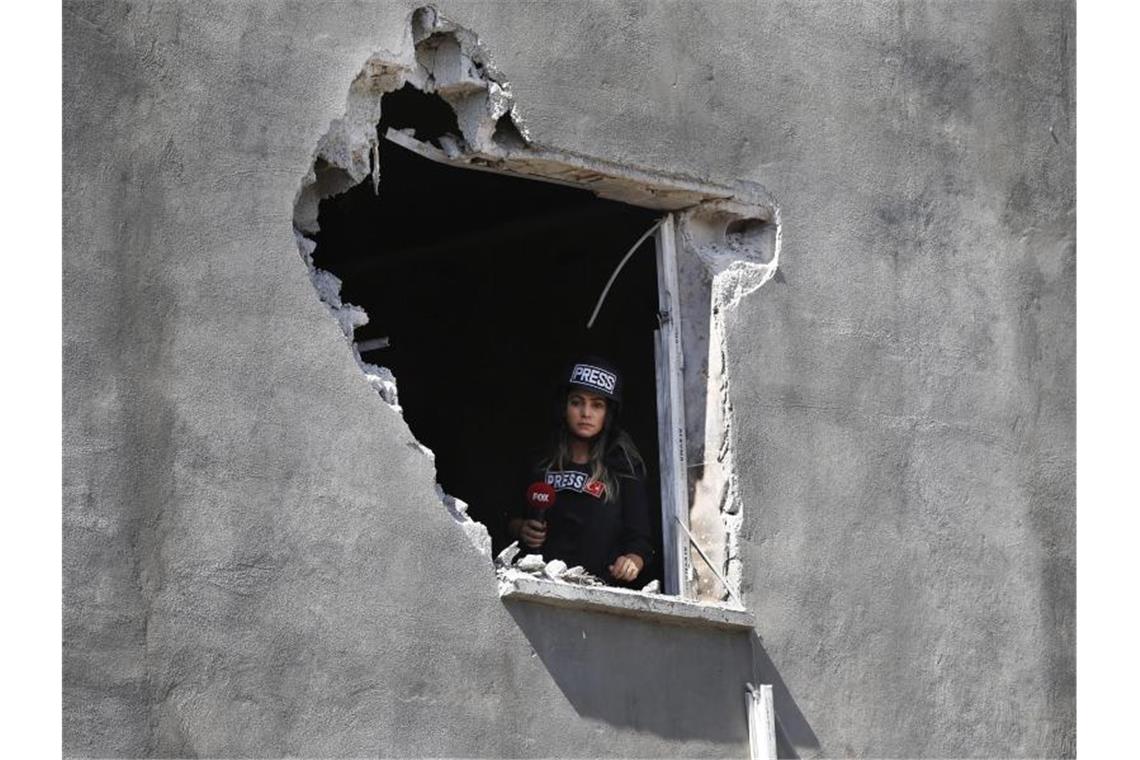 Eine Journalistin schaut aus einem Loch in der Wand eines Hauses in Akçakale, das von einem Mörser aus Syrien beschädigt wurde. Niemand wurde durch den Angriff verletzt. Foto: Lefteris Pitarakis/AP/dpa