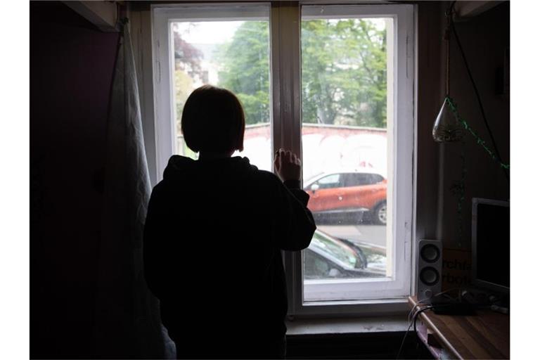 Eine Jugendliche sitzt in einem abgedunkelten Zimmer. Foto: Paul Zinken/dpa/Illustration