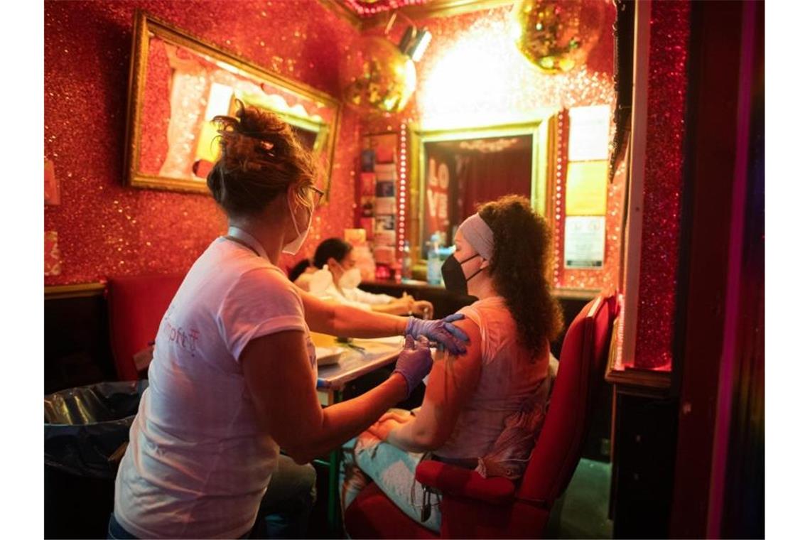 Eine junge Frau lässt sich in einer Bar nahe der Reeperbahn im Hamburger Stadtteil St. Pauli gegen das Coronavirus impfen. Foto: Daniel Reinhardt/dpa