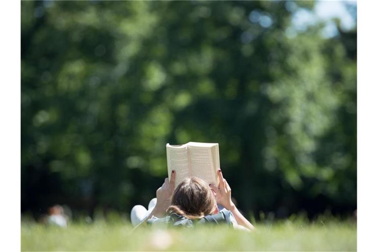 Eine junge Frau liest ein Buch. Foto: Friso Gentsch/Archivbild
