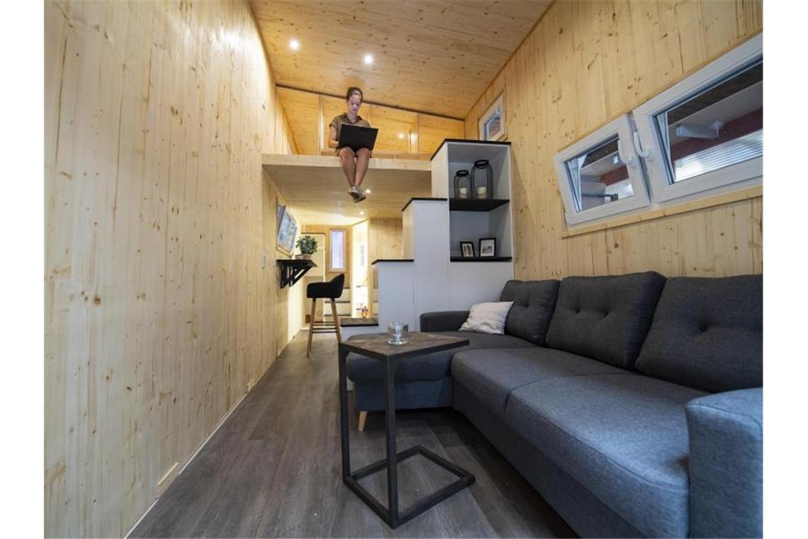 Tiny House als XS-Eigenheim - Baustein gegen Wohnungsnot Eine junge Frau sitzt mit ihrem Laptop auf einer Empore eines XS-Hauses. Foto: Guido Kirchner