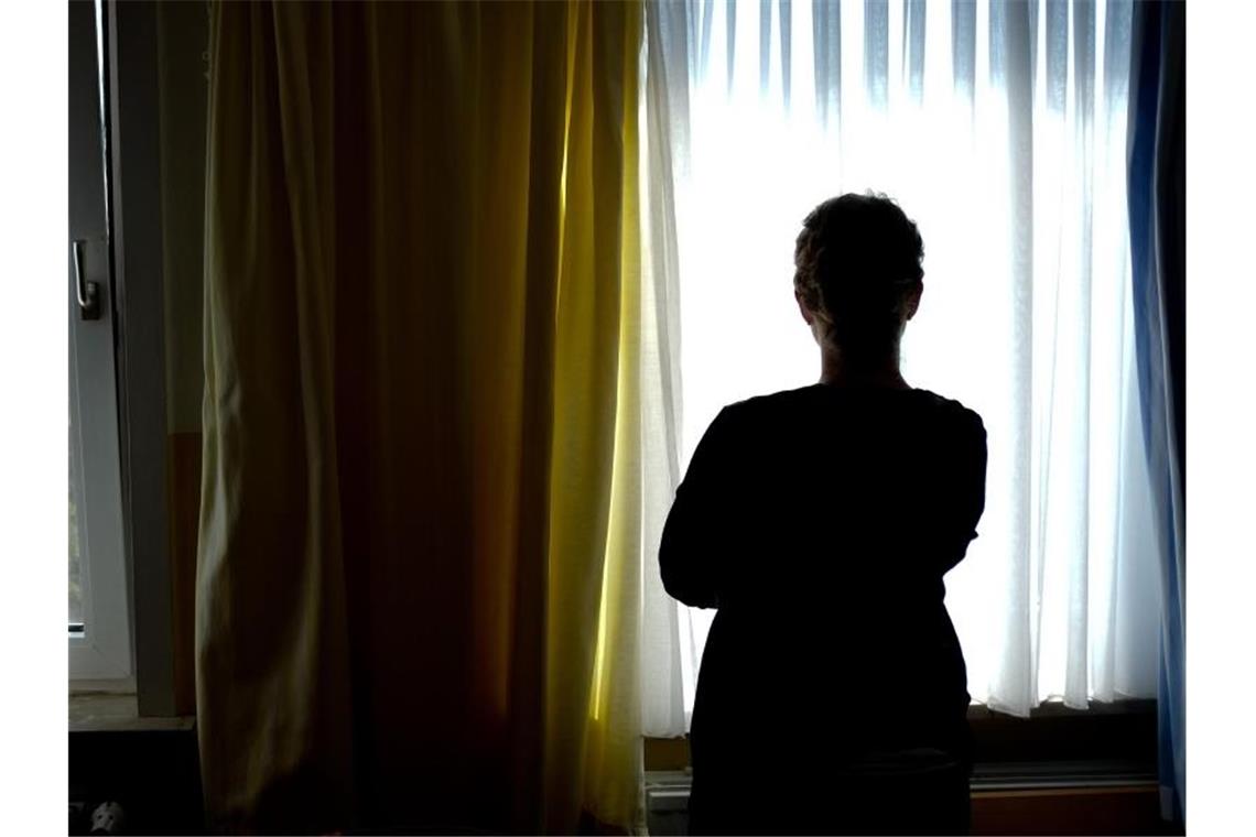 Eine junge Frau steht in einem Zimmer eines Frauenhauses. Foto: Peter Steffen/dpa/Symbolbild