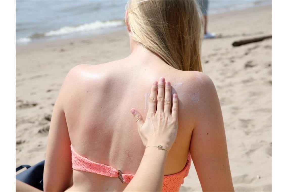 Eine junge Frau wird am Strand mit Sonnencreme eingerieben. Foto: Bodo Marks