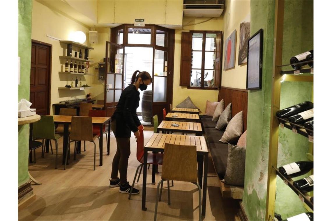 Innengastronomie auf Mallorca wieder geöffnet Eine Kellnerin mit Maske bereitet in Palma den Innenraum eines Restaurants für das Tagesgeschehen vor. Foto: Clara Margais/dpa
