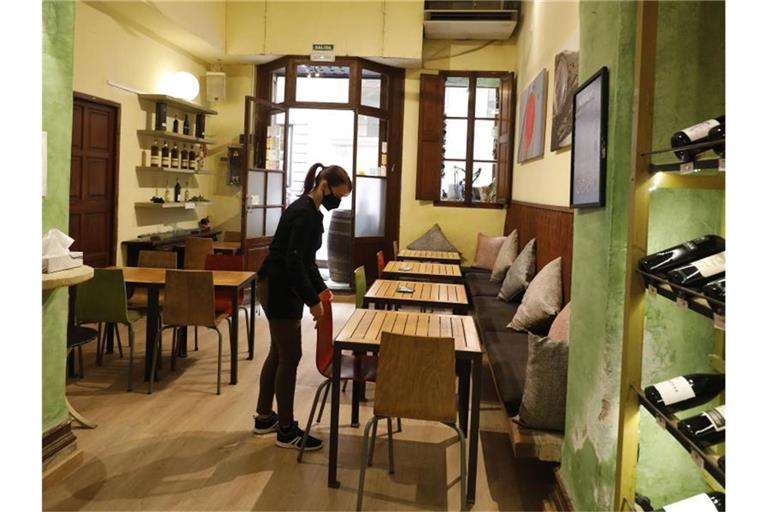 Eine Kellnerin mit Maske bereitet in Palma den Innenraum eines Restaurants für das Tagesgeschehen vor. Foto: Clara Margais/dpa