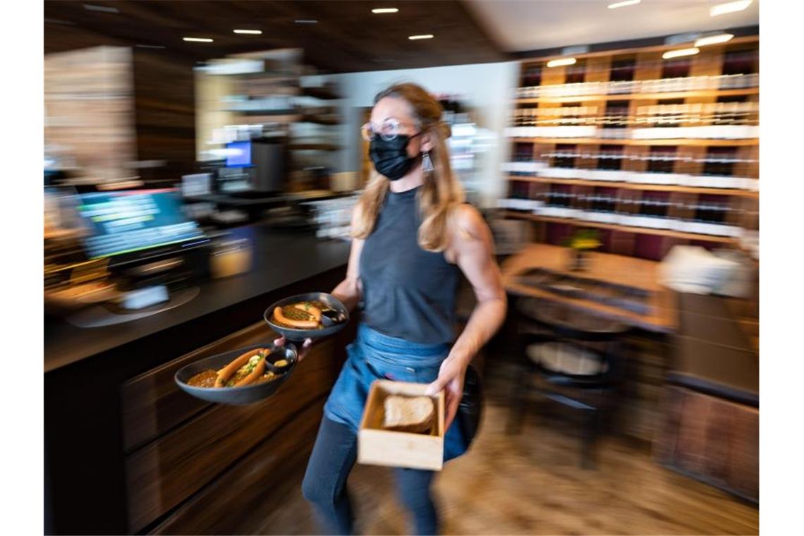 Strengere Corona-Regeln für Ungeimpfte in Baden-Württemberg Eine Kellnerin trägt in einem Restaurant Essensteller. (Archivbild). Foto: Marijan Murat/dpa