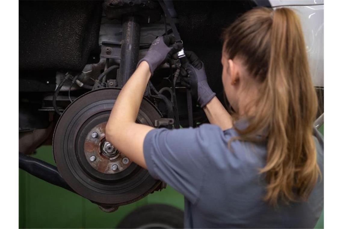 Eine Kfz-Mechanikerin wechselt in einer Werkstatt die Bremsscheibe eines Autos. Foto: Marijan Murat/dpa