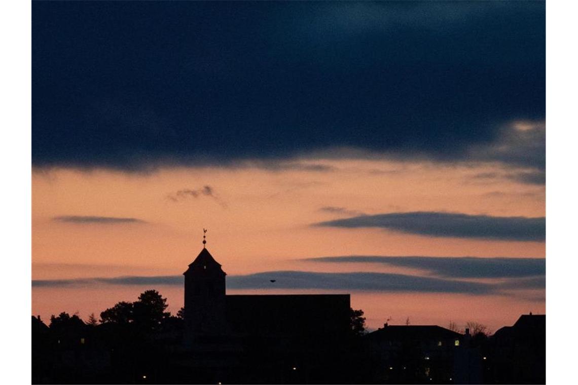 Eine Kirche zeichnet sich vor morgendlichem Himmel ab. Foto: Marijan Murat/dpa